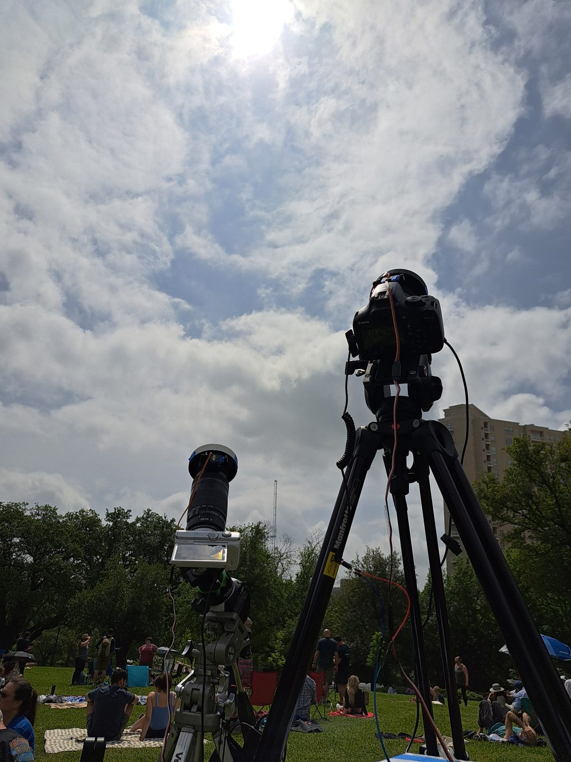 Two cameras pointed towards a mostly cloudy sky.